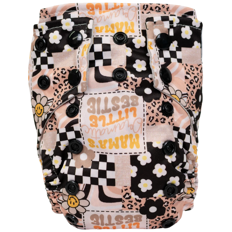 Tiny Tushies Newborn AIO cloth diaper with floral and checkered pattern, featuring adjustable snaps and tummy panels.