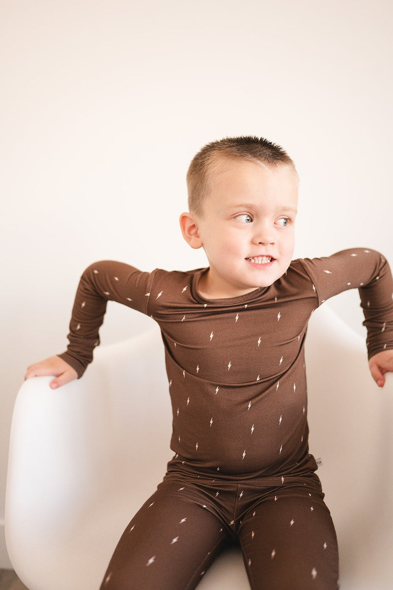 Child wearing Brown Lightning two-piece pajama set, bamboo blend, snug fit, cozy and eco-friendly.