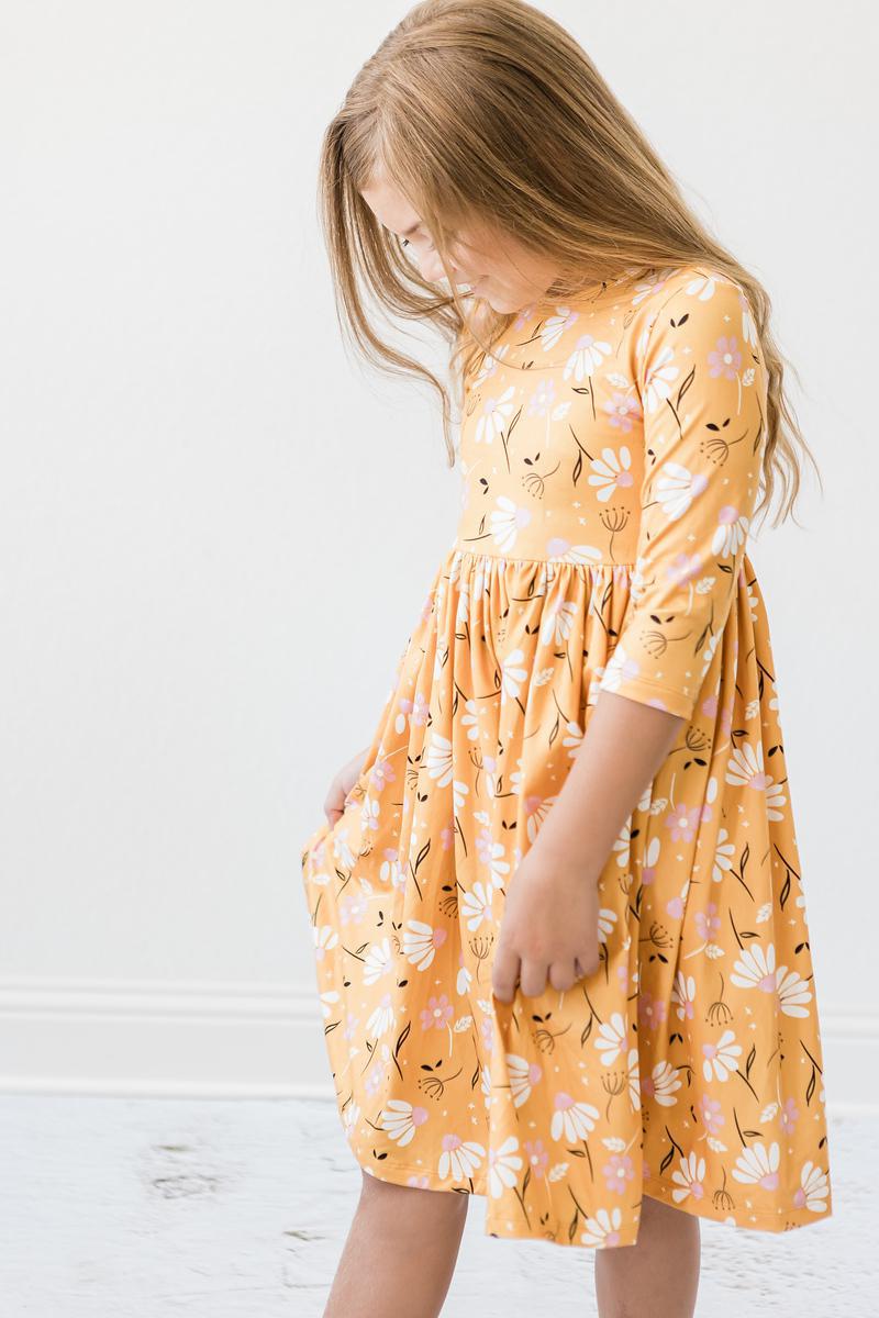 Twirl dress with 3/4 sleeves and pockets in an autumn dandelion print, shown with a full twirling skirt.