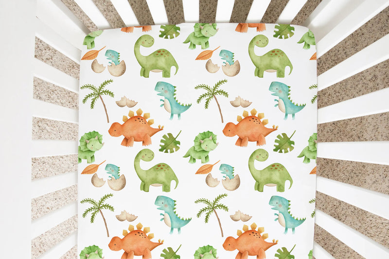 Fitted crib sheet with dinosaur pattern in a crib.