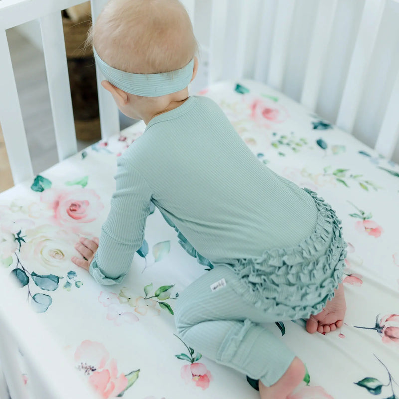 Baby on peach floral fitted crib sheet, standard size, soft fabric.