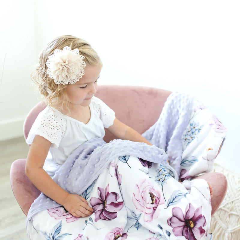 Vintage floral baby and toddler blanket on a child in a pink chair with ruffled pillow.