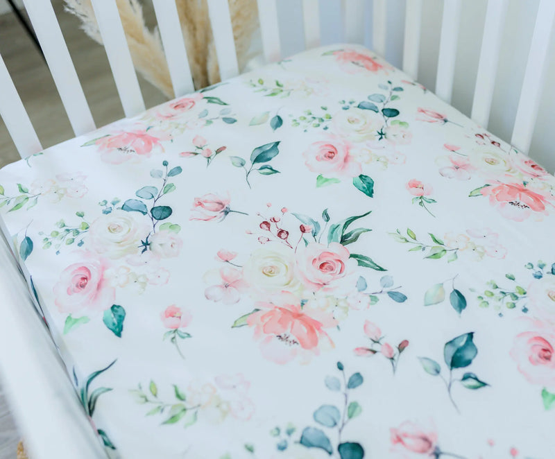 Peach floral fitted crib sheet displayed on a crib mattress.