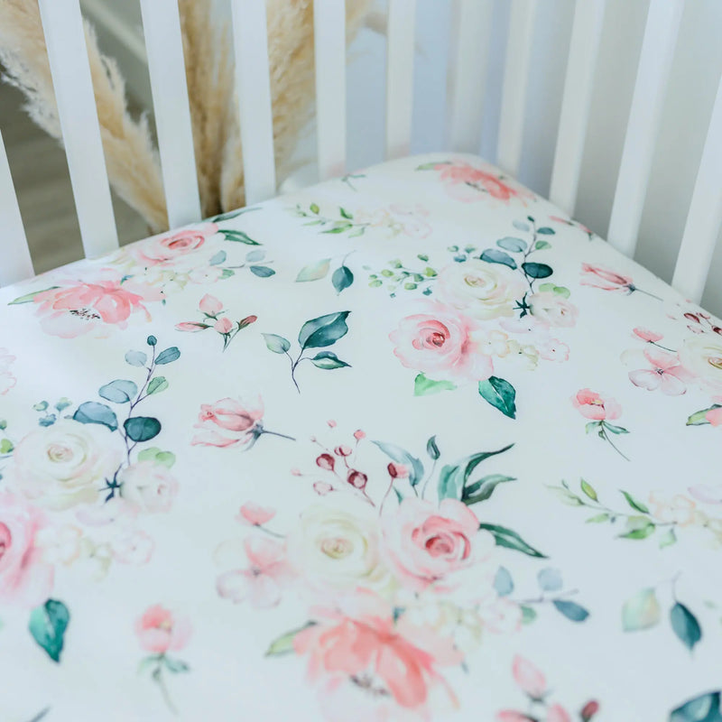 Peach floral fitted crib sheet on a crib mattress.