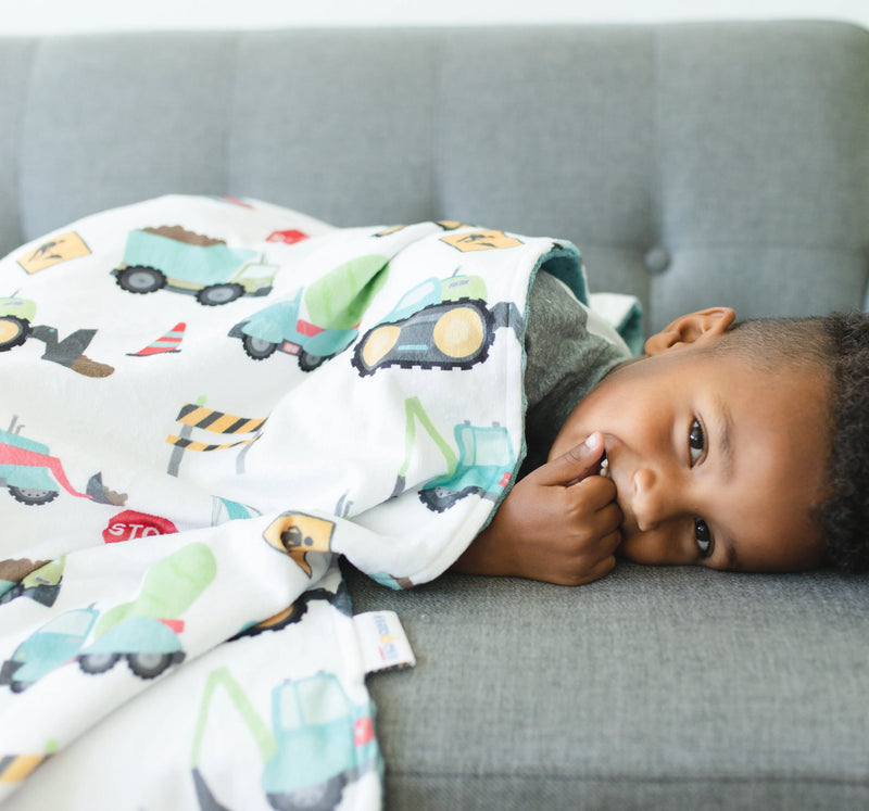 Baby & toddler minky blanket with construction trucks pattern on a child, 30x40 inches, soft and sensory-stimulating.