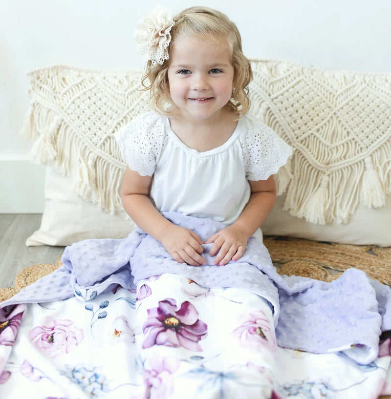 Baby sitting on vintage floral baby and toddler blanket with minky texture.