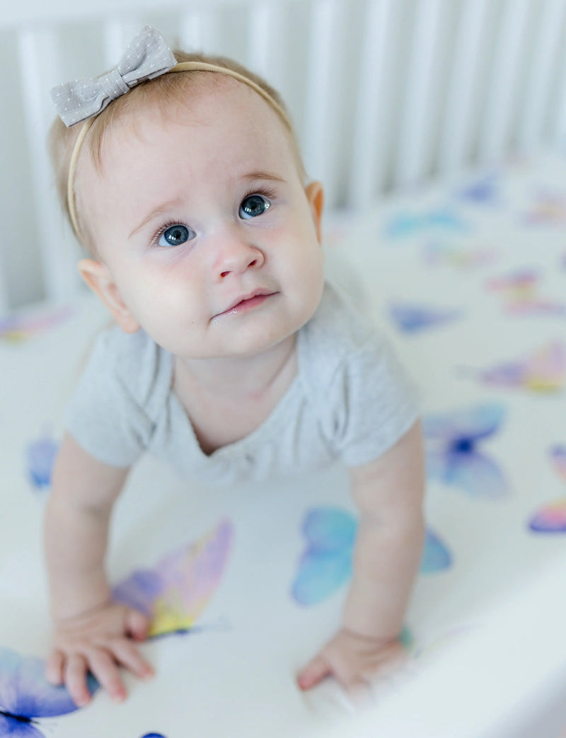 Fitted crib sheet with butterfly pattern used as a backdrop for baby photos.