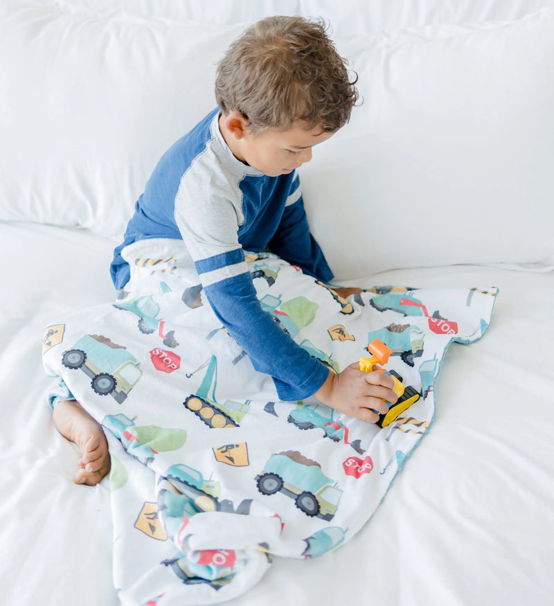 Baby with construction truck-themed minky blanket.
