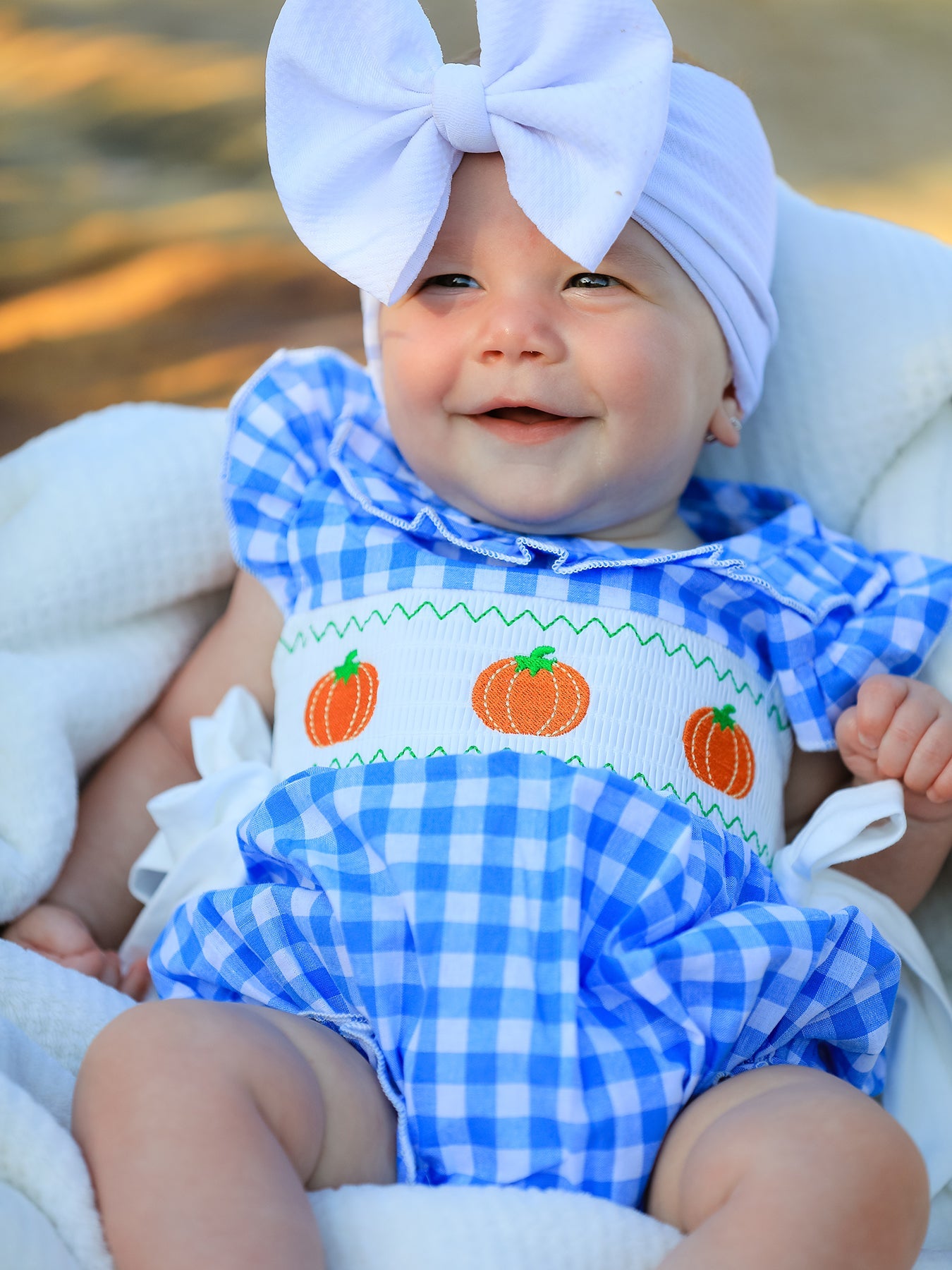 Baby girl romper in blue with pumpkin smock embroidery across the chest for fall and Halloween.