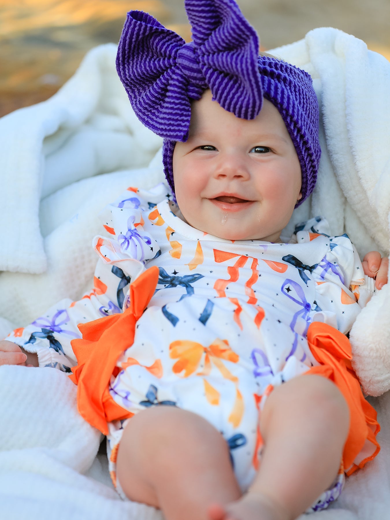 Long-sleeve girls romper with a Halloween bow print in festive colors and ruffle trim.
