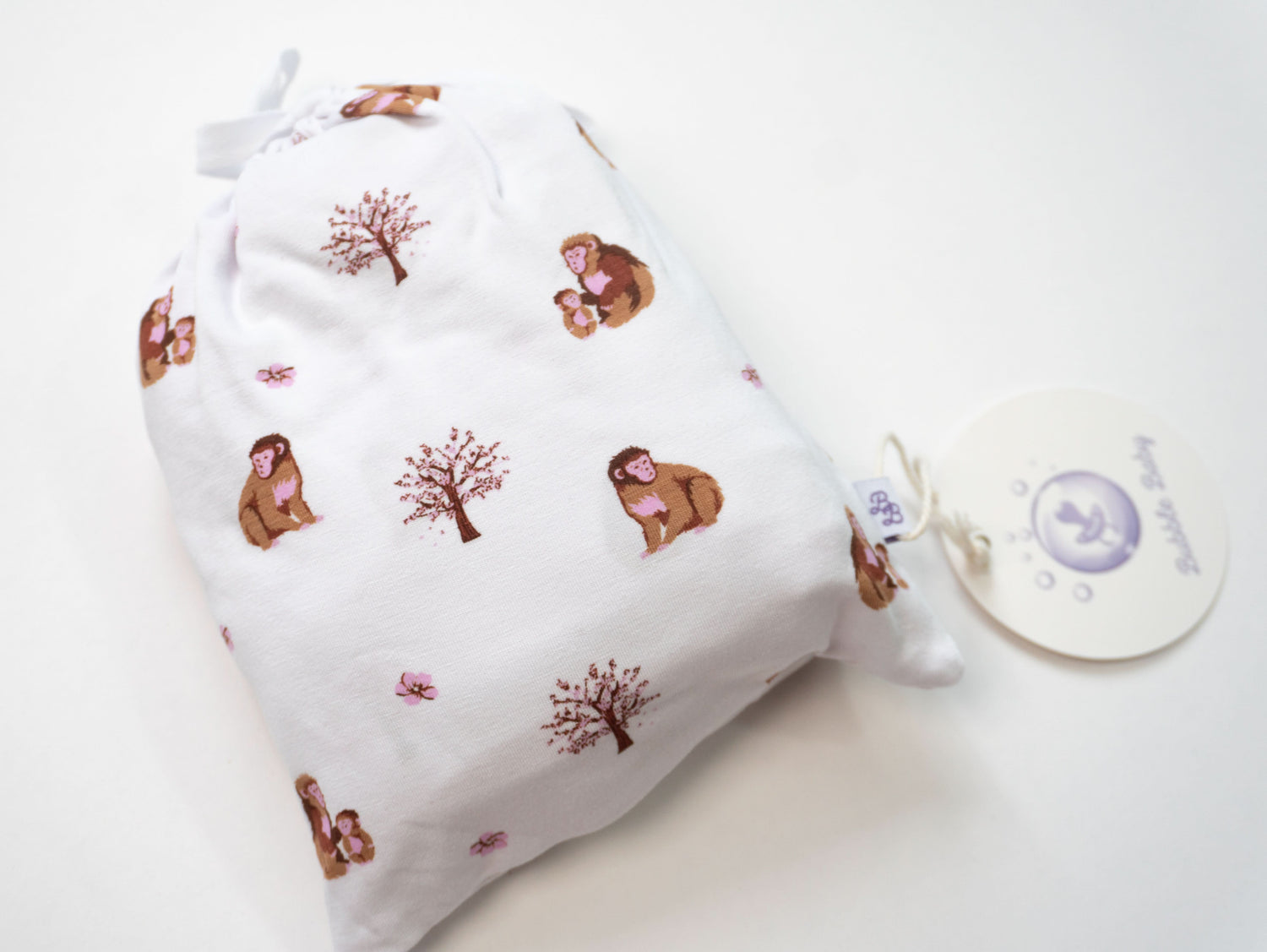 Changing pad cover in bamboo viscose with a macaque monkey print, fitted over a nursery changing pad.