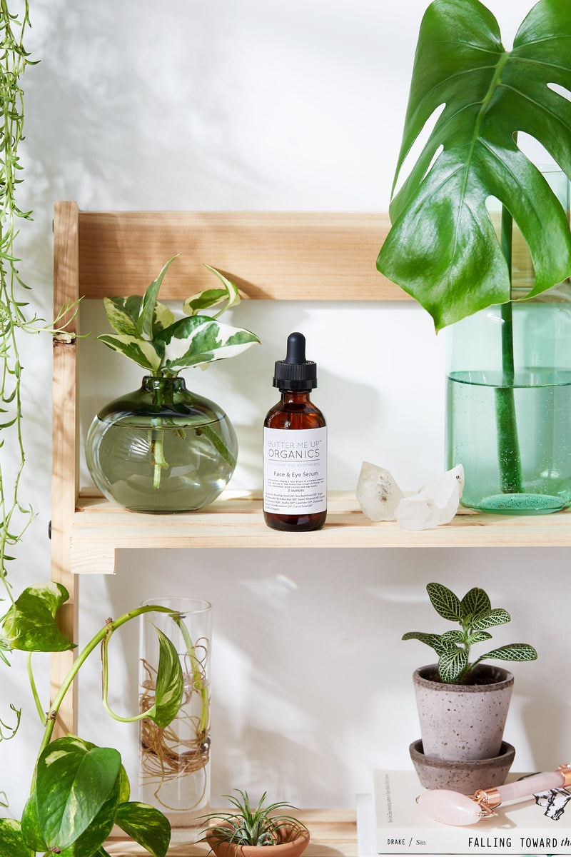 Organic Face & Eye Serum on a wooden shelf with plants, promoting natural skincare.