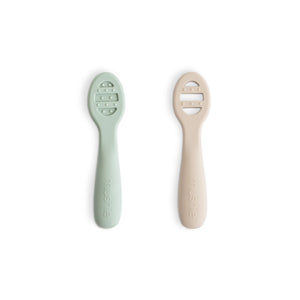 Set of flat baby feeding spoons, one solid and one with open slots, both with raised sensory dots along the sides.