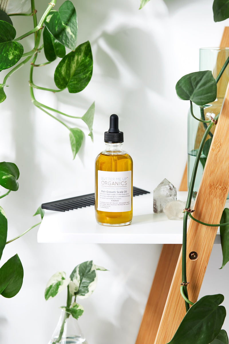 Organic scalp treatment in glass bottle surrounded by plants on a shelf.