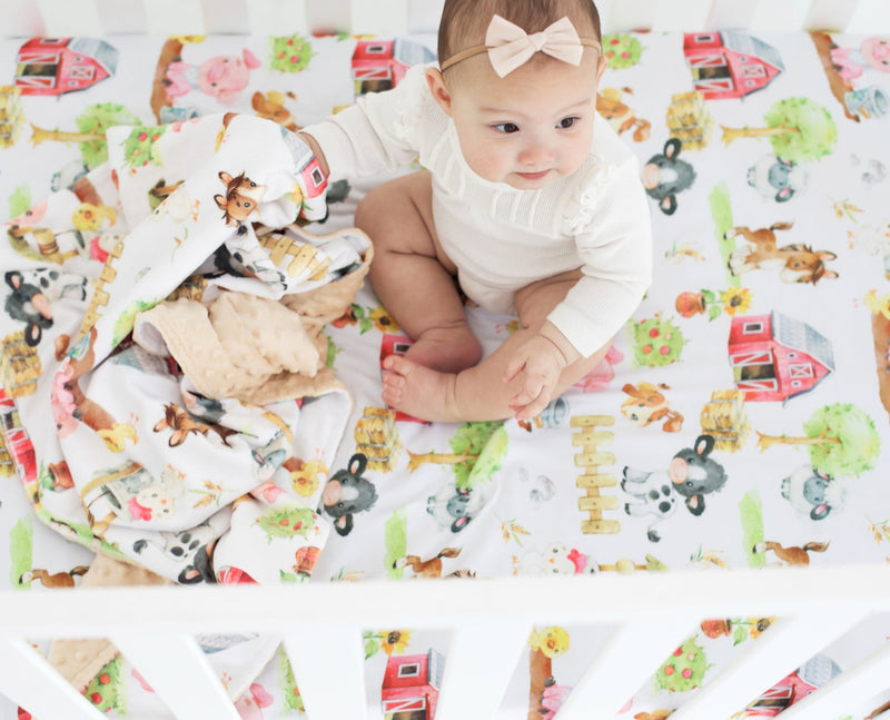 Fitted crib sheet with farm animal design in baby crib.