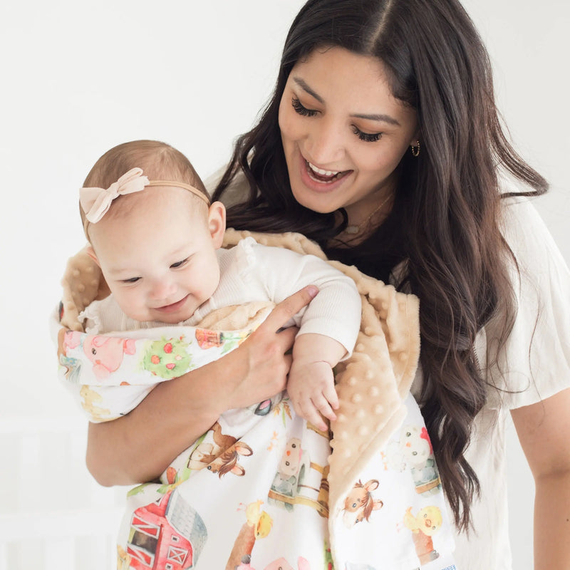 Baby and toddler minky blanket with farm animal print held by mother and child.