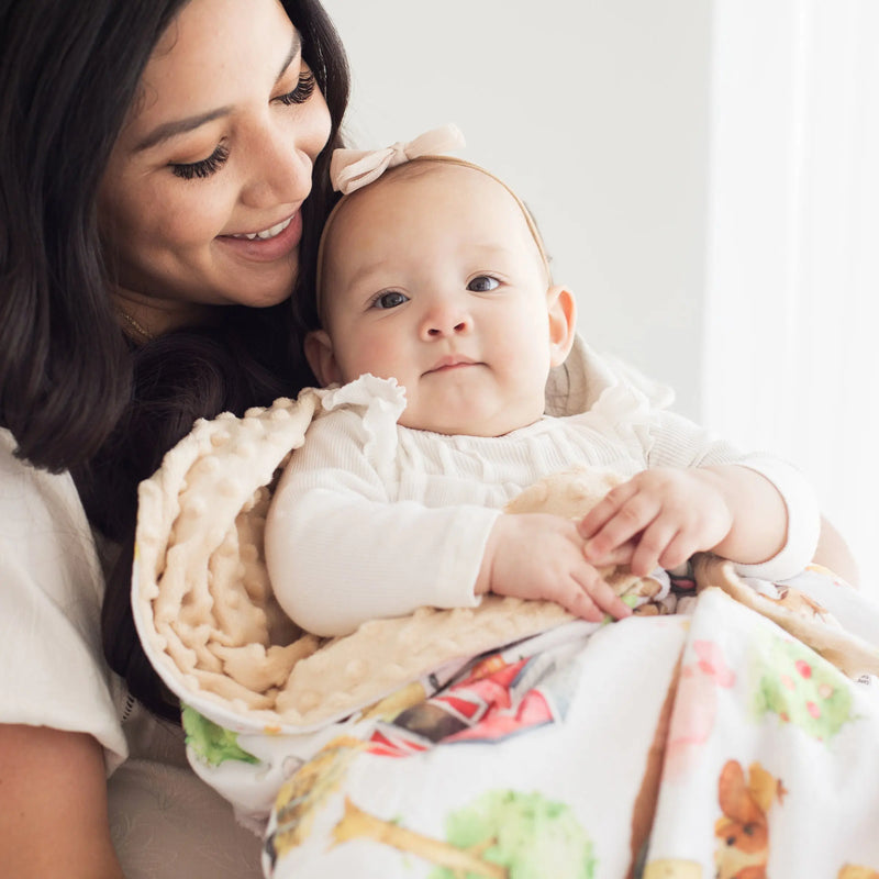 Baby wrapped in farm animal design minky blanket with mother, soft and cozy.