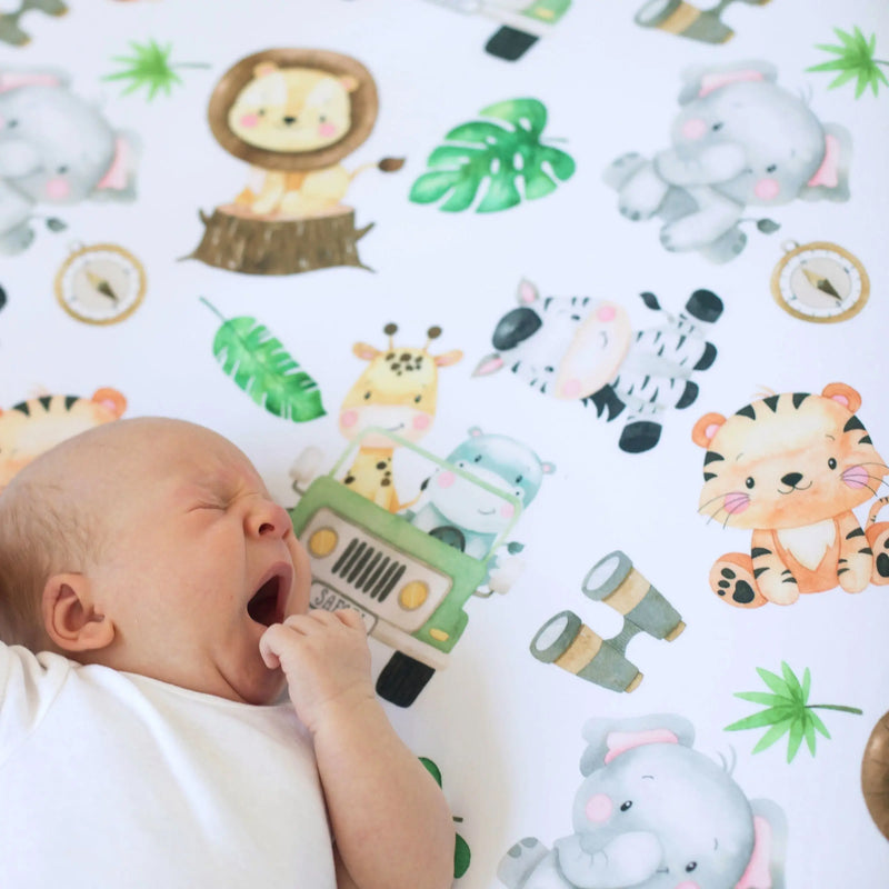 Fitted crib sheet with safari animal print featuring elephants, lions, zebras, and giraffes; ideal for a nursery.