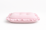 Close-up of a soft pink gingham ruffle baby lounger cover from Little Mae & Co, on a white background.