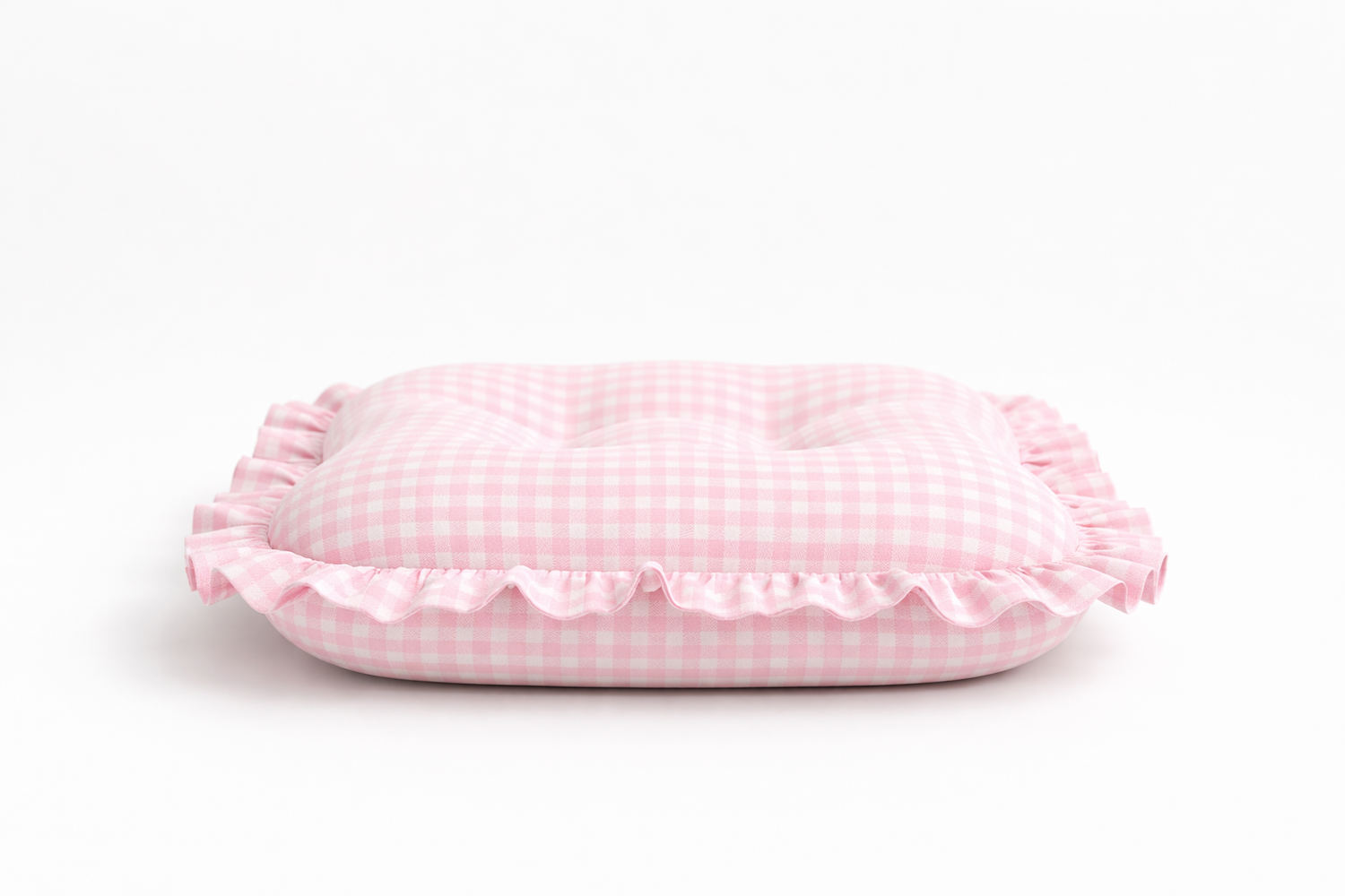 Close-up of a soft pink gingham ruffle baby lounger cover from Little Mae & Co, on a white background.