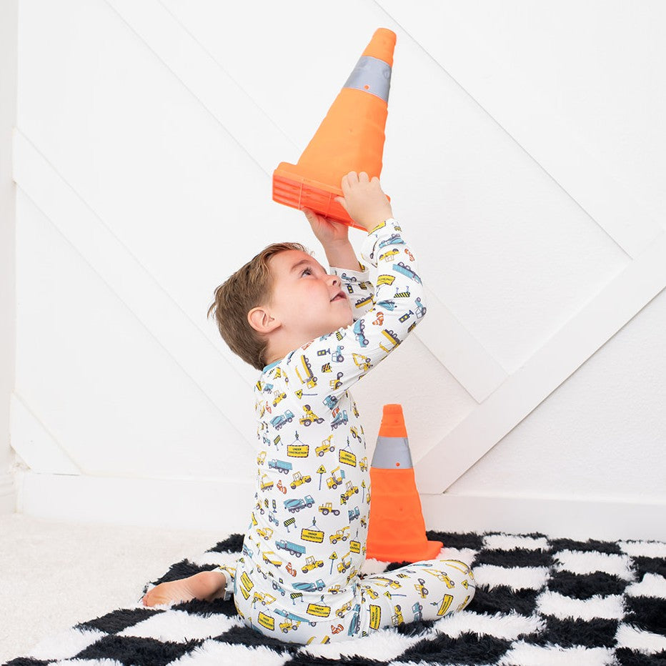 Long-sleeve two-piece pajamas with a construction and builder theme, worn by a child playing with toys.