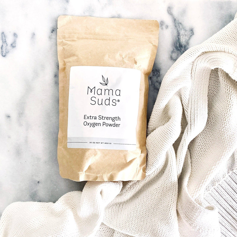 Eco-friendly MamaSuds Extra Strength Oxygen Powder package on marble surface with white fabric.