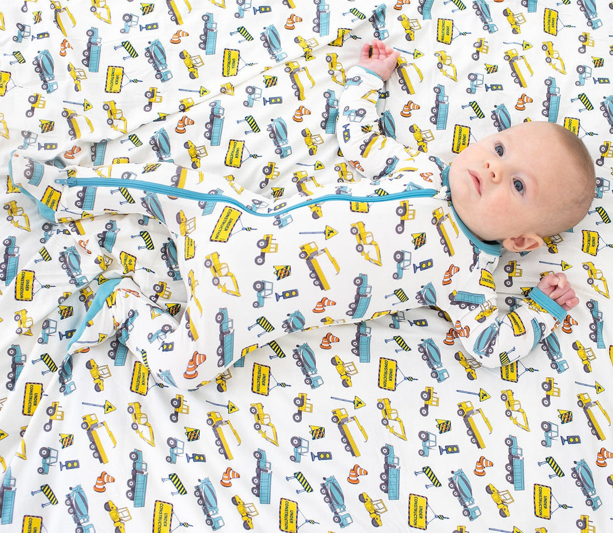 Baby footie pajamas with a busy builders construction print, long sleeves, full-length zipper, and covered feet