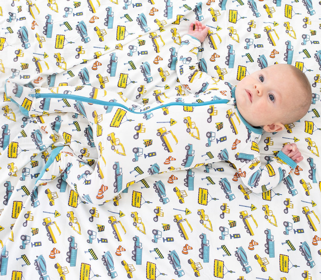 Baby footie pajamas with a busy builders construction print, long sleeves, full-length zipper, and covered feet