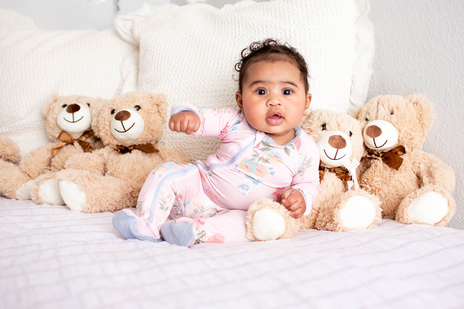 Baby footie pajamas in a small pink and white ditzy floral print with a full-length zipper and footed legs.