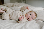 Baby wearing a soft, organic long sleeve cotton romper from LUCY LUE ORGANICS, gentle on skin.