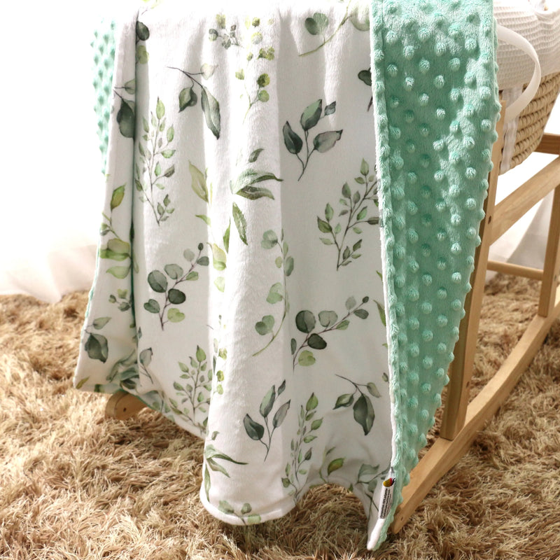 Premium baby and toddler minky blanket in eucalyptus greenery design on a rocking chair.