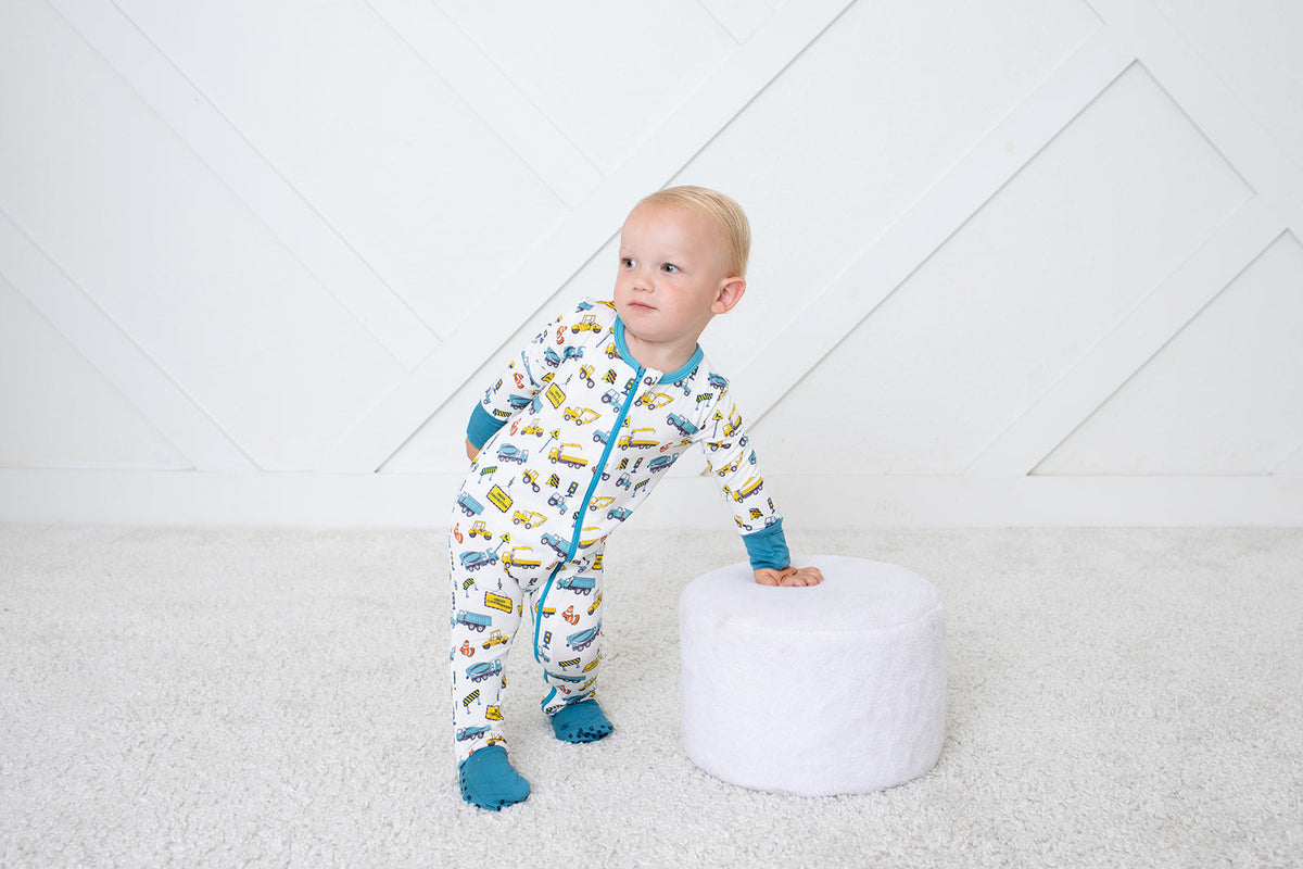 Baby coverall in a playful construction-themed print with long sleeves, footed legs, and a full-length two-way zipper.