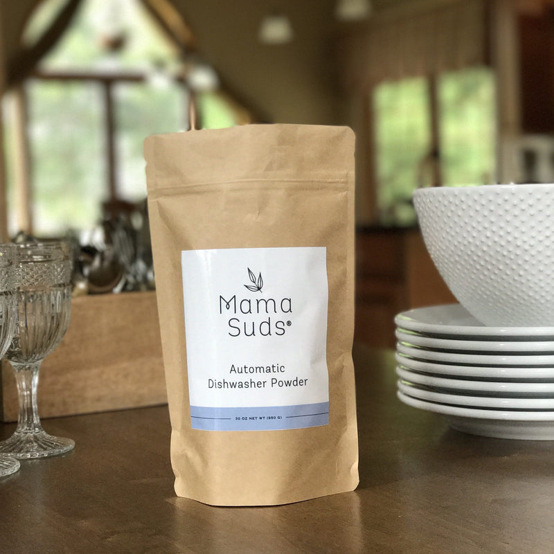 Eco-friendly non-toxic dishwasher powder package labeled MamaSuds on kitchen counter.