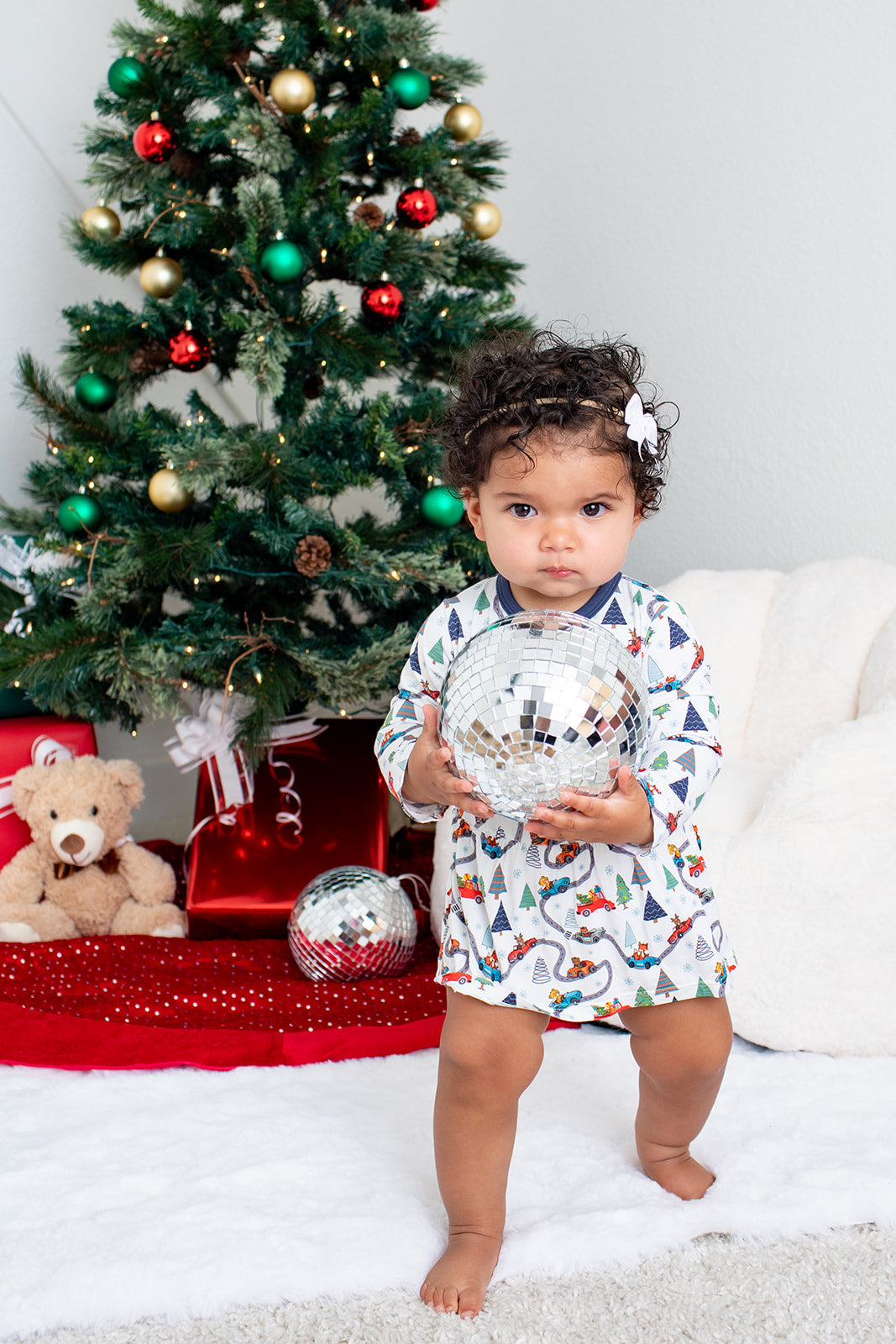 Long-sleeve baby bodysuit dress with a festive holiday design and snap closure at the inseam.
