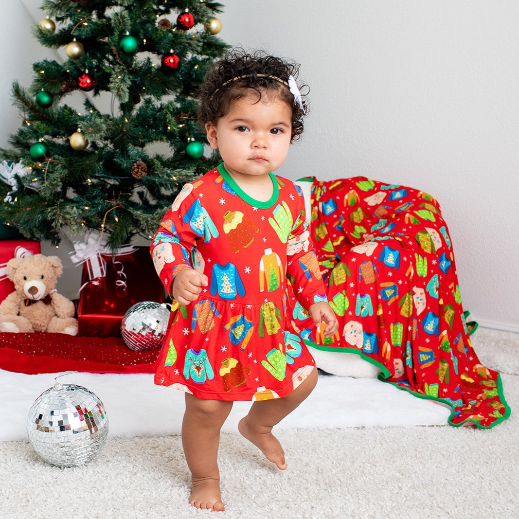 Long-sleeve baby bodysuit dress with a festive ugly-sweater holiday design and snaps at the inseam.