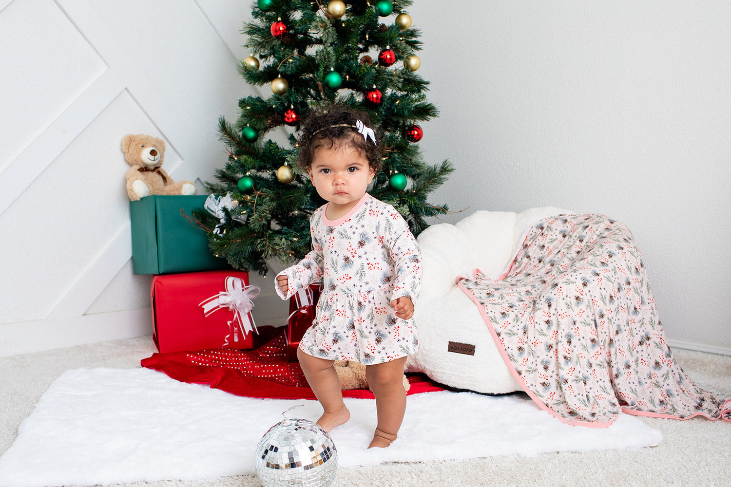 Long-sleeve baby bodysuit dress with a pine tree pattern and snap closure at the inseam