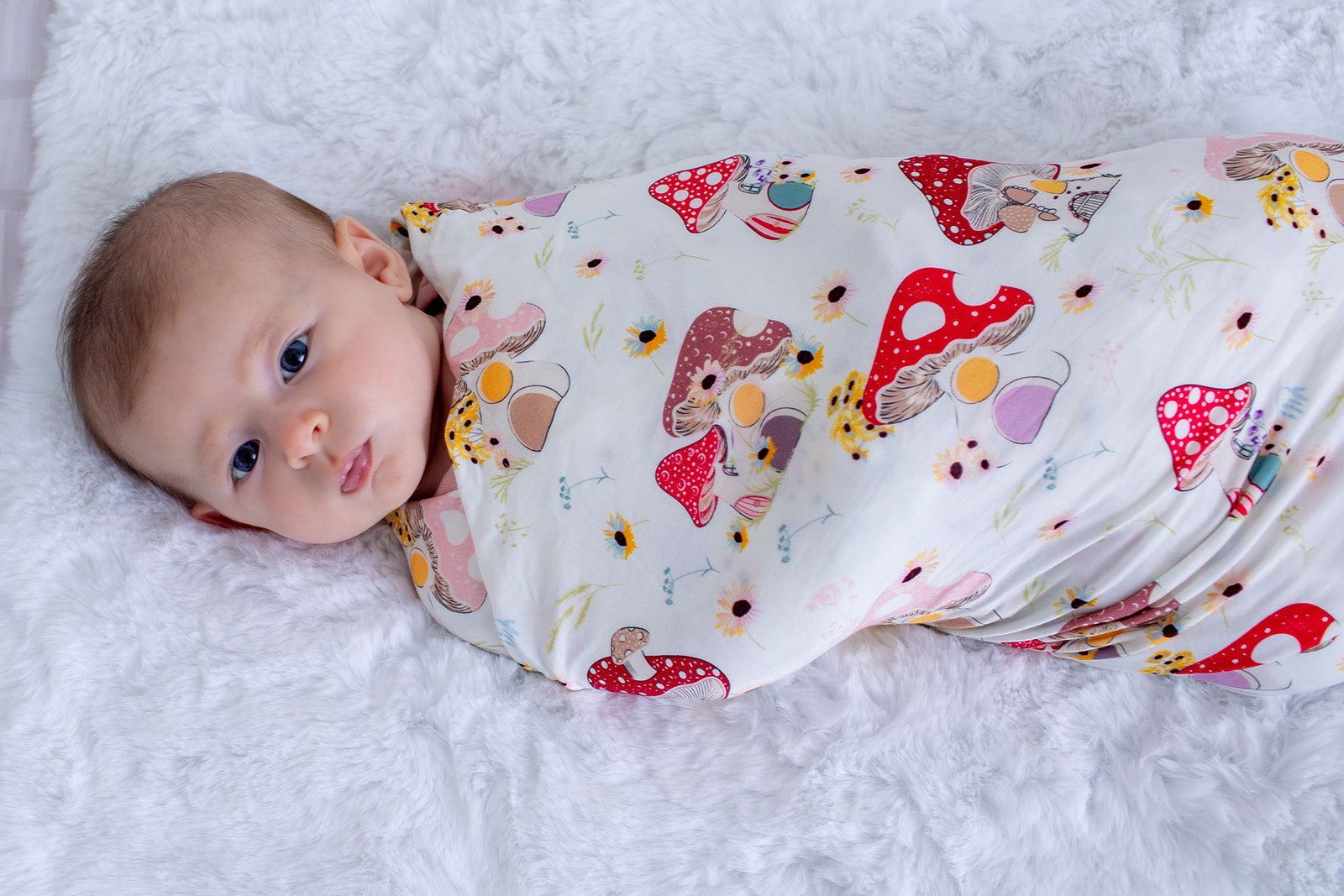Swaddle blanket in pink with a floral and mushroom print, spread out flat