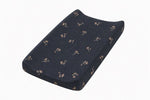 Changing pad cover in light blue with a small white dandelion print, fitted over a contoured changing pad