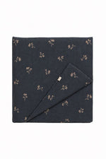 Quilted crib blanket with blue dandelion print on white cotton, hand-tufted stitching visible