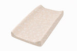 Beige changing pad cover with a white floral print, fitted over a contoured changing pad