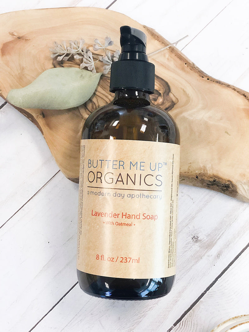 Organic Oatmeal Hand Soap bottle on wooden board with plant decoration.