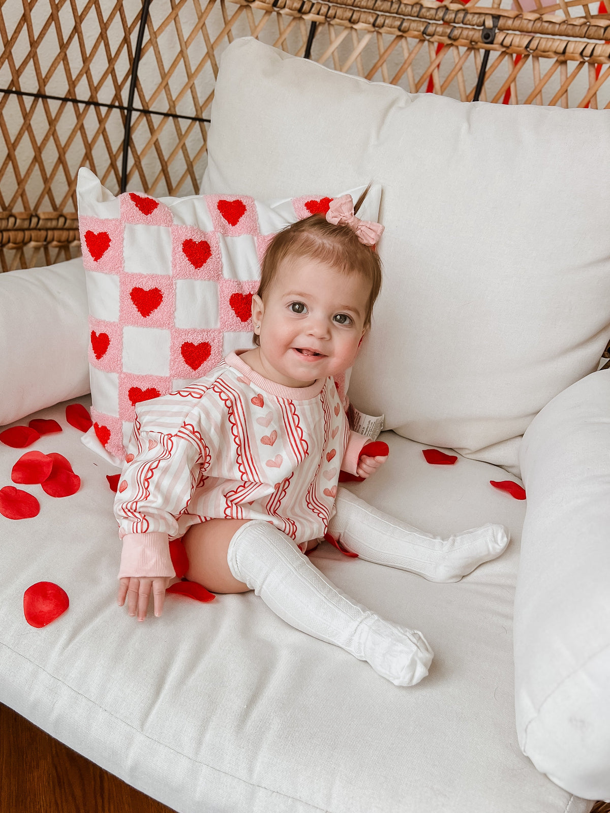 Baby wearing Laced with Love organic cotton sweatshirt romper with lace trim detail, smiling.