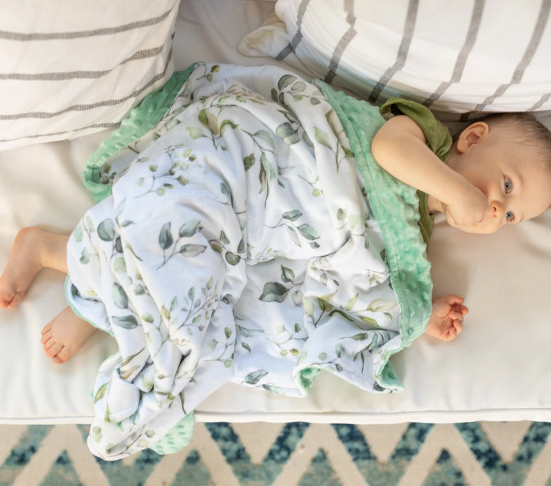 Premium baby and toddler minky blanket in eucalyptus greenery pattern on a baby.