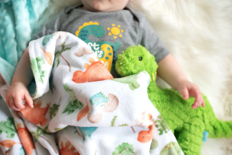 Premium baby and toddler minky blanket with dinosaur pattern on a cozy setting.