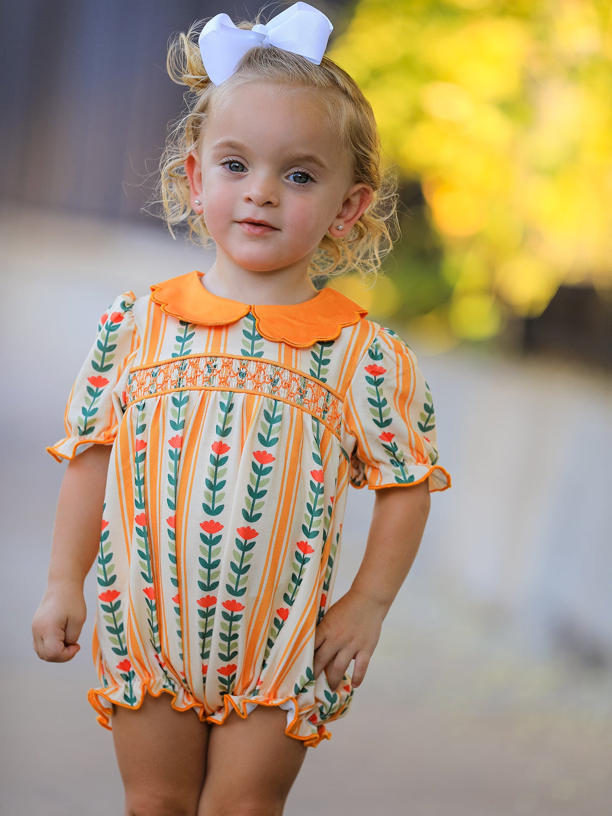 Baby girls romper in a floral stripe print with a scalloped petals collar and smocked detailing across the front