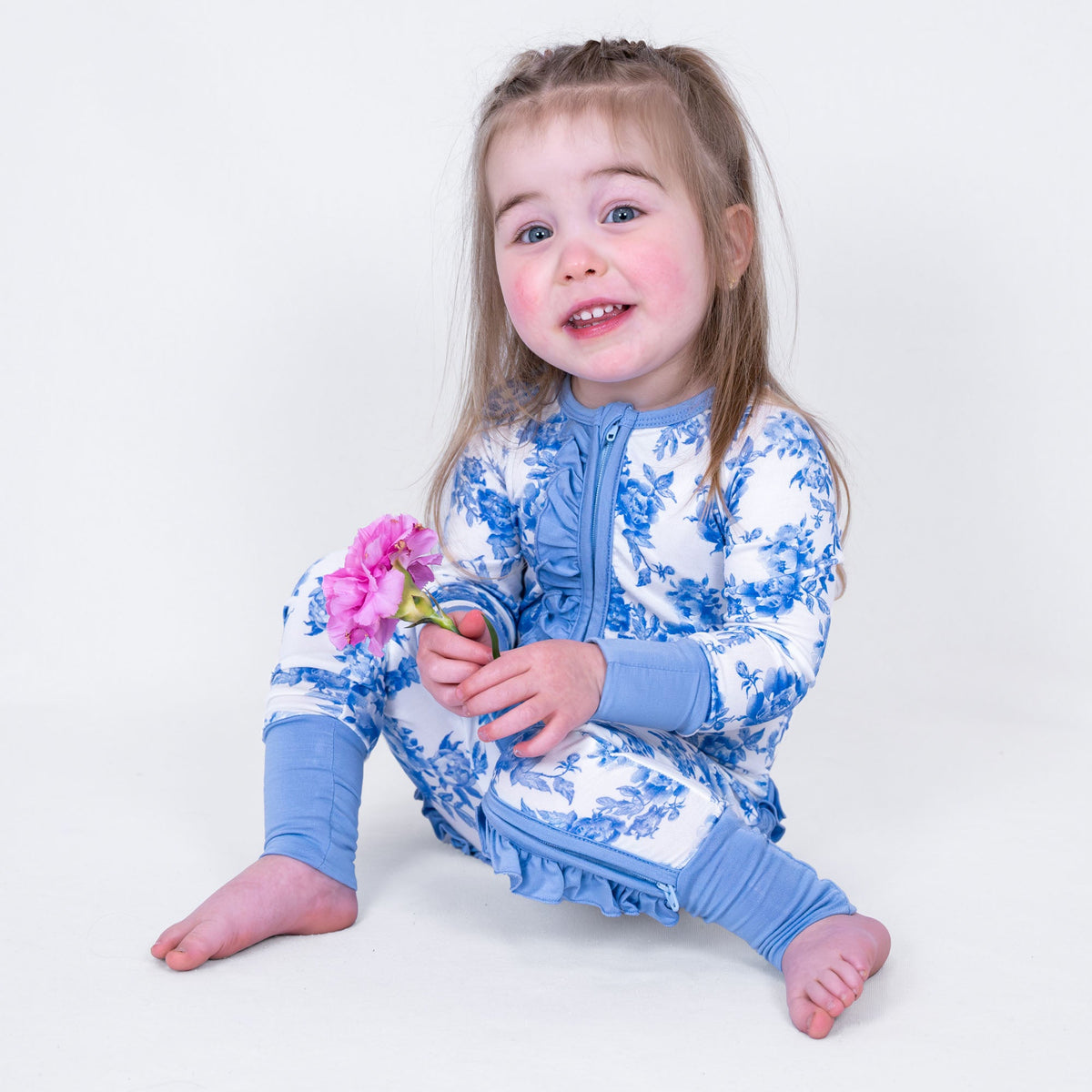 LollyBanks baby one-piece pajama with pink peony floral print and ruffles, front zipper closure.