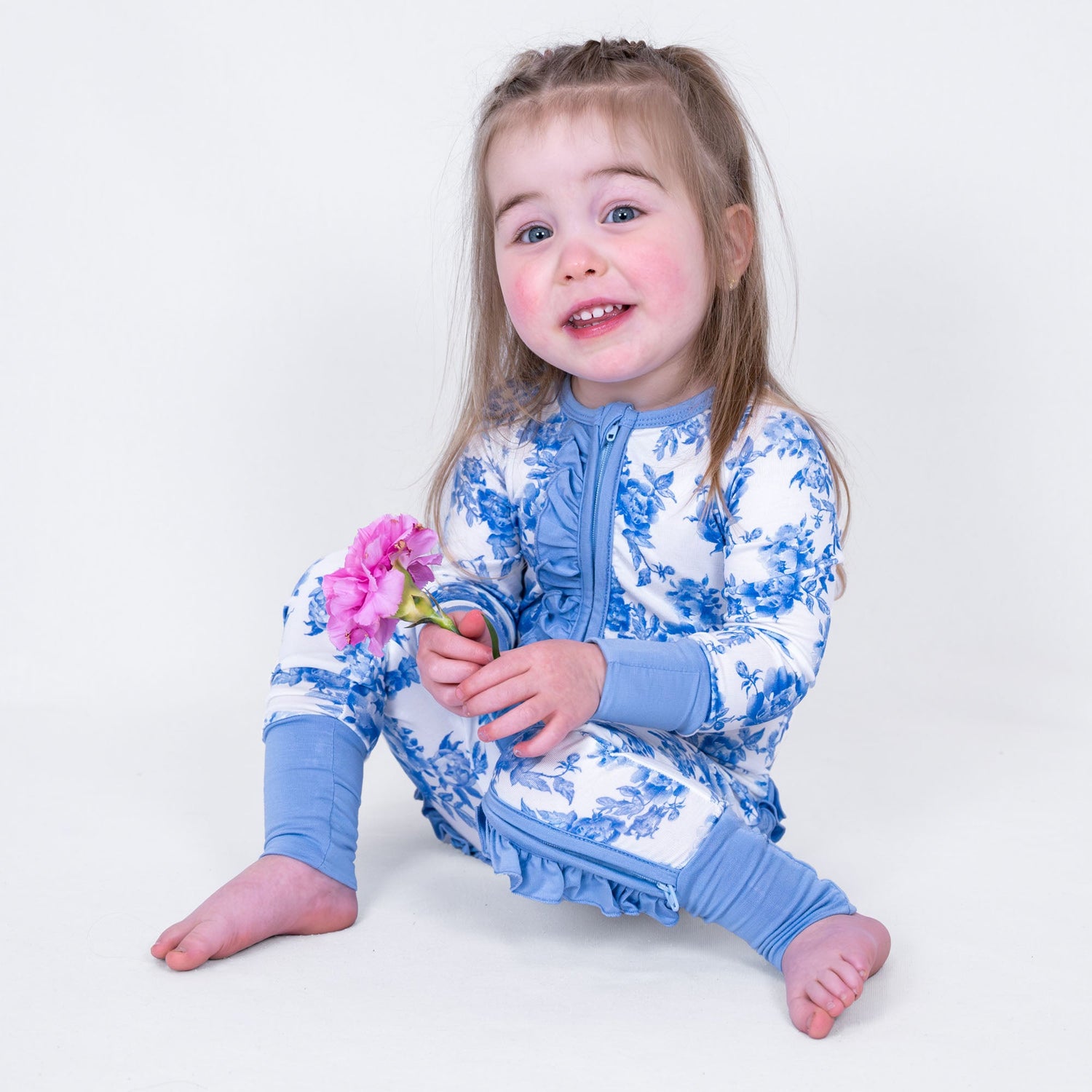 LollyBanks baby one-piece pajama with pink peony floral print and ruffles, front zipper closure.