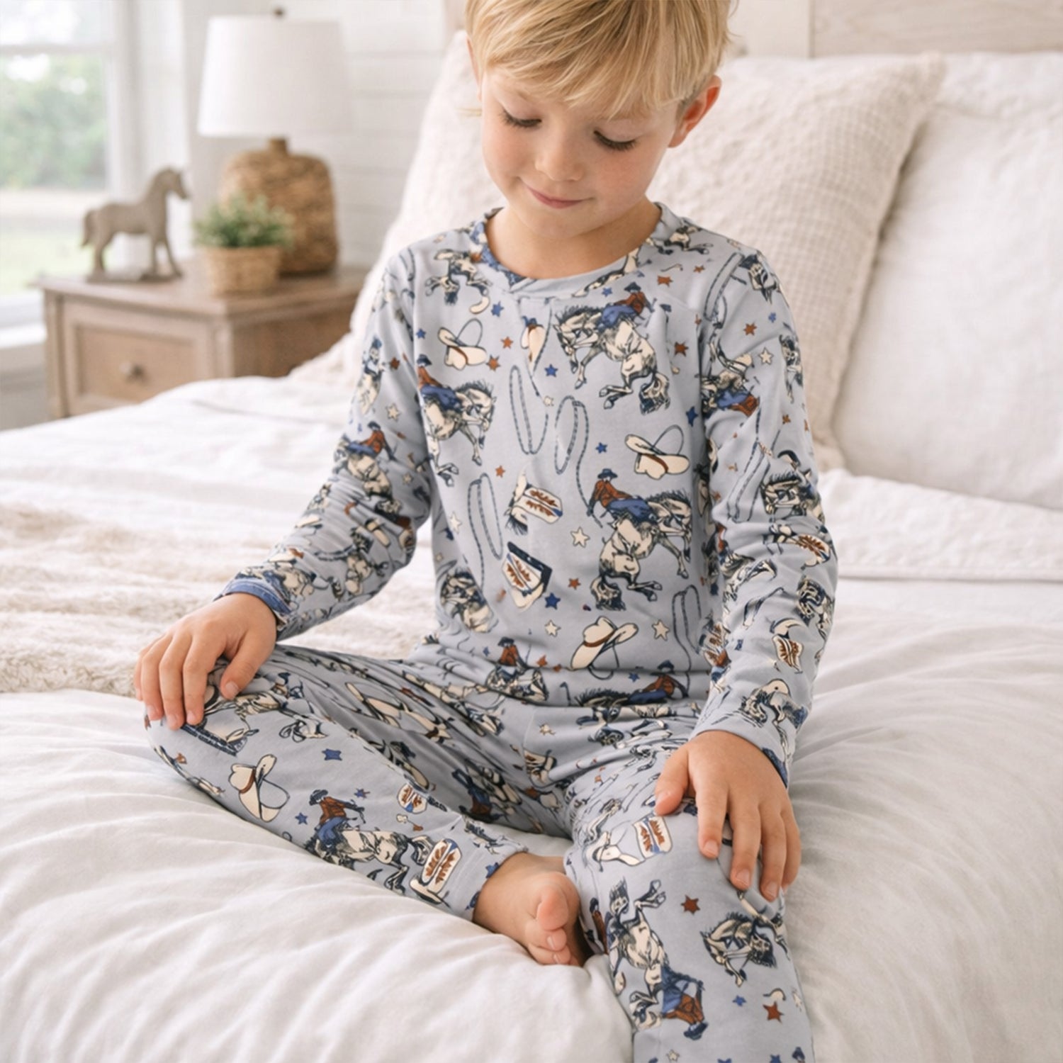 Two-piece children's pajama set with a Western rodeo print of bucking broncos, cowboy hats, and lassos, crewneck top and