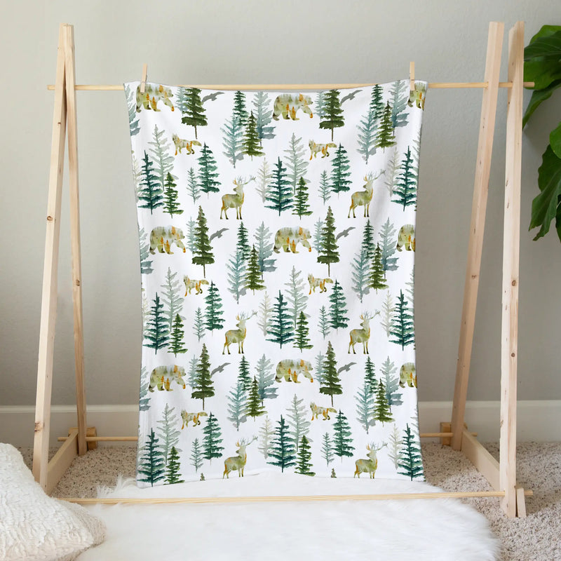 Baby & Toddler Minky Blanket with forest print hanging on wooden rack.