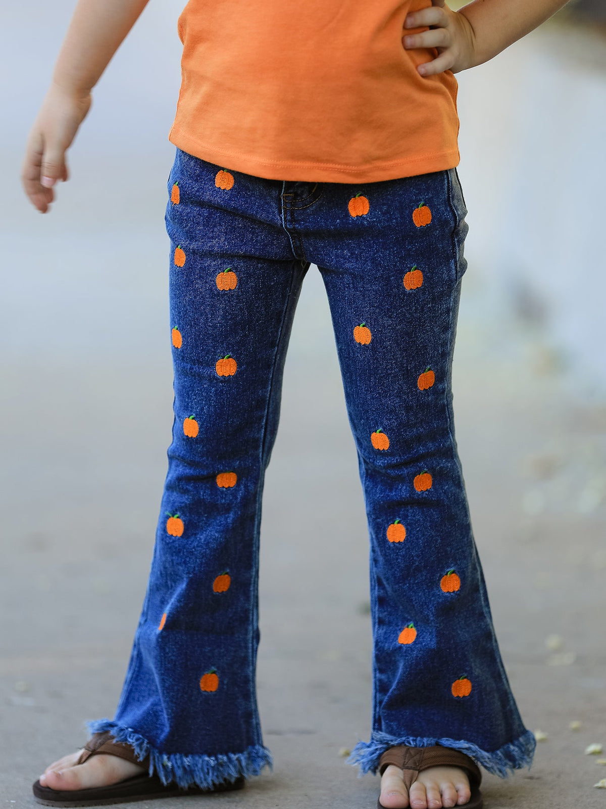 Girls blue denim flare jeans with orange pumpkin embroidery and a fringe hem at the ankles